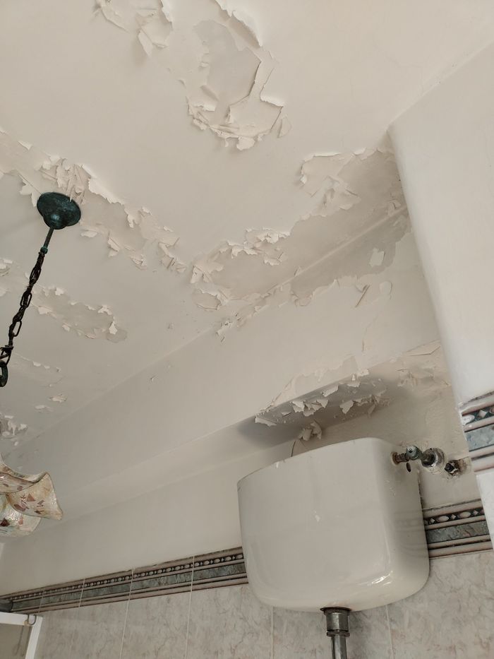Soffitto di un bagno con la pittura che si sfoglia per l'umidità